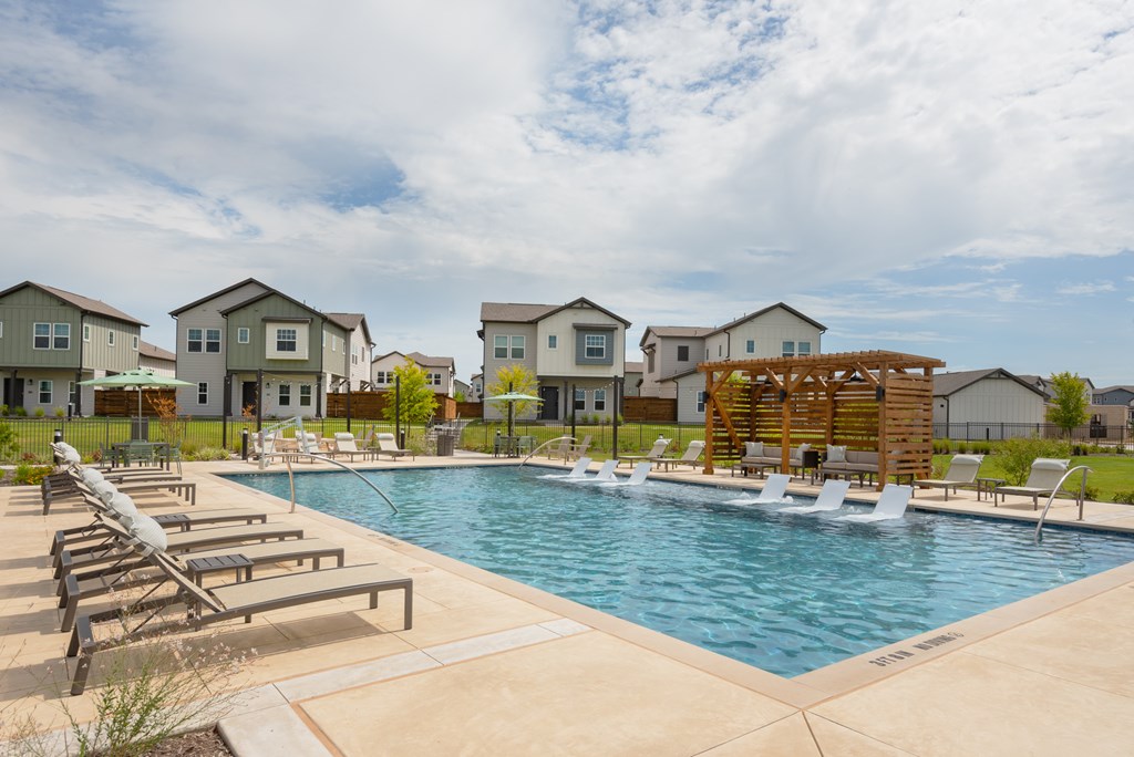 A pool surrounded by lounge chairs and a wooden structure in the middle of the pool.