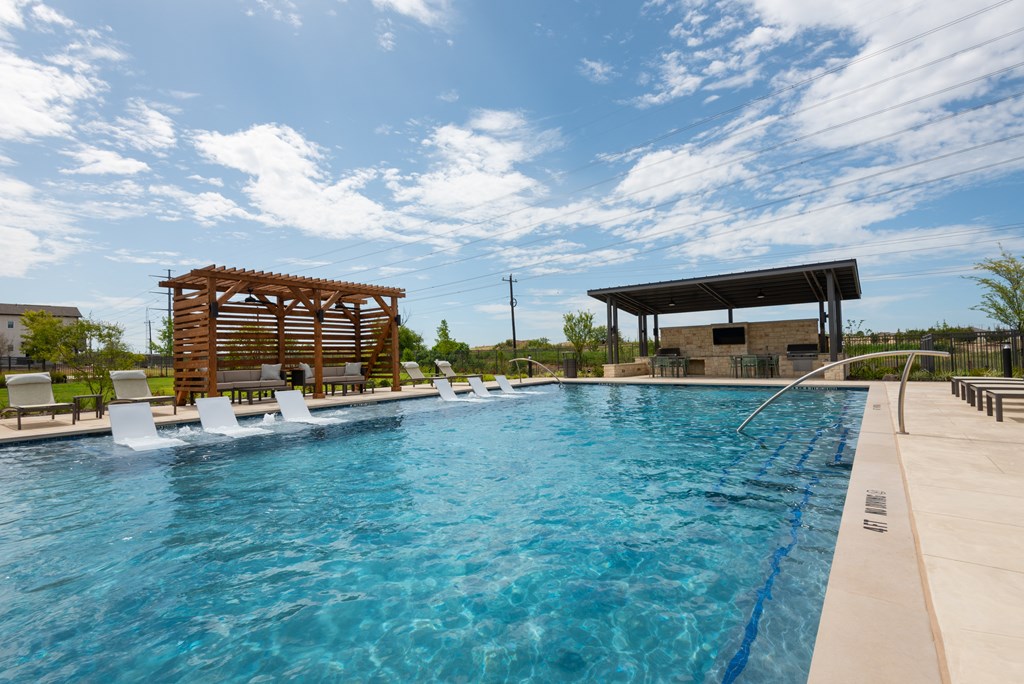 A large swimming pool with a wooden structure and lounge chairs.
