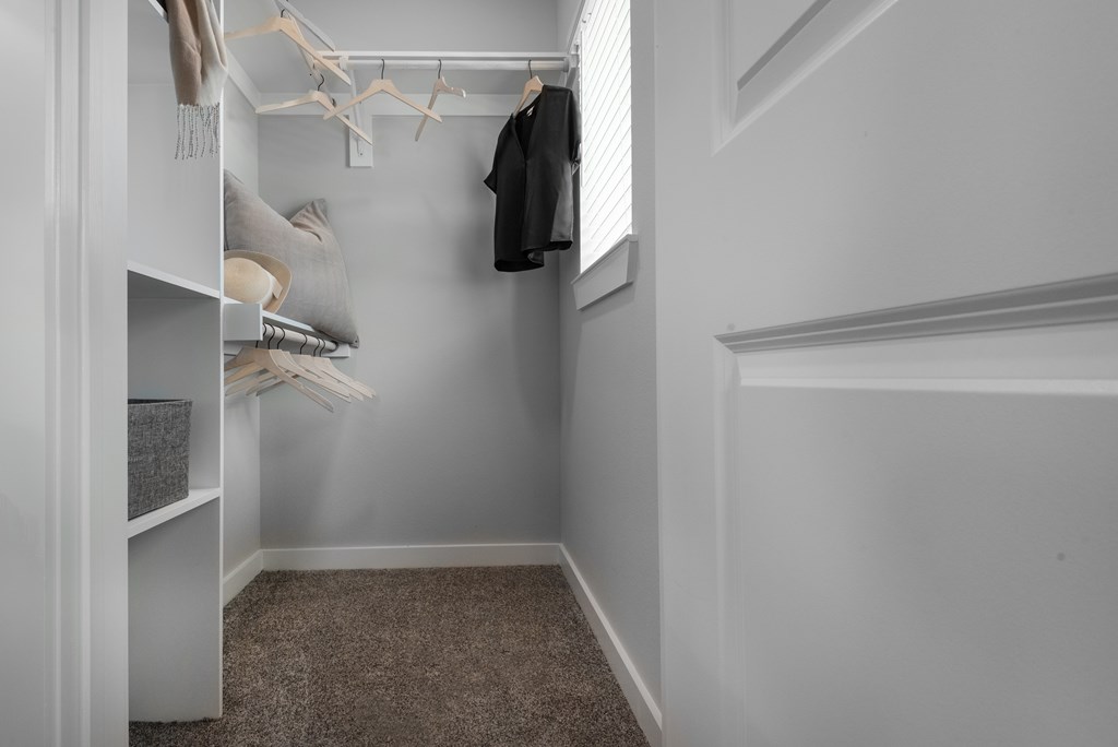 A small closet with a coat hanging on the rod.