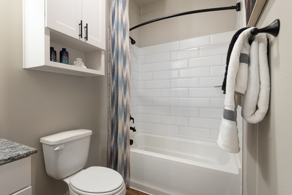 A white toilet sits next to a white bathtub in a bathroom.