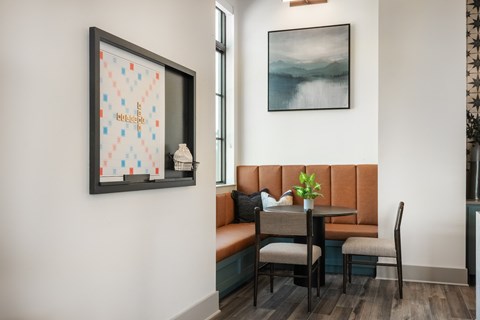 A dining area with a table set for two and a framed picture on the wall.