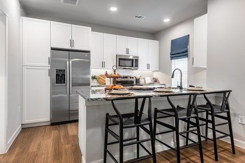 A kitchen with a refrigerator, microwave, and a table with chairs.