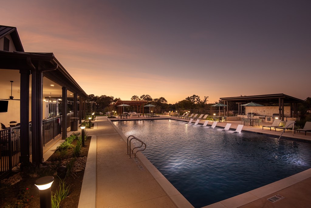 A pool area with lounge chairs and a building on the left.