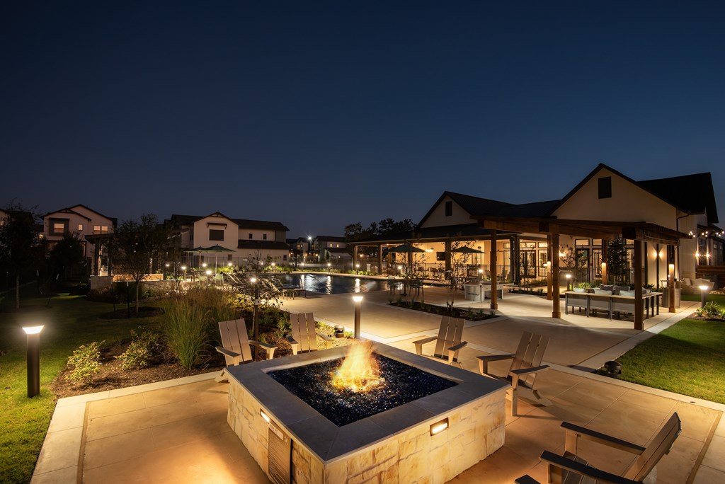 A fire pit in the middle of a patio surrounded by chairs.