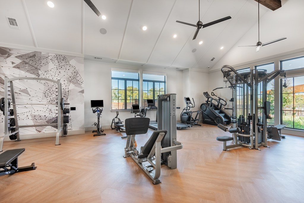 A spacious gym with a variety of equipment and a ceiling fan.