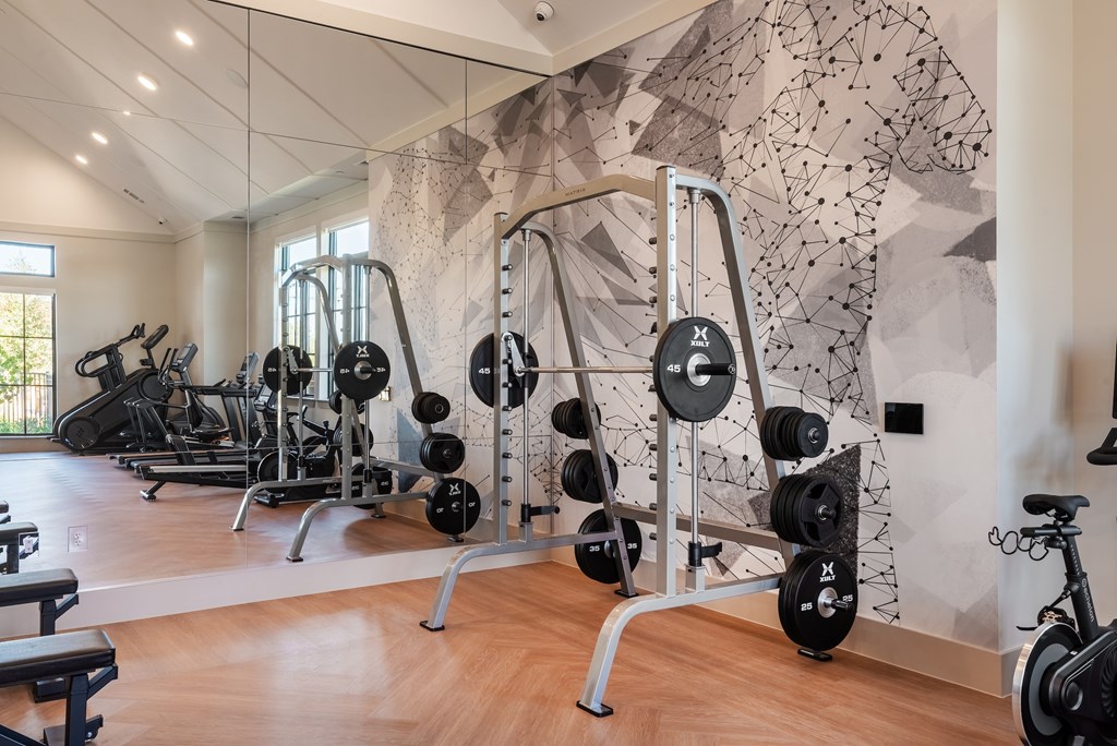 A gym with a variety of equipment including weights and a stationary bike.