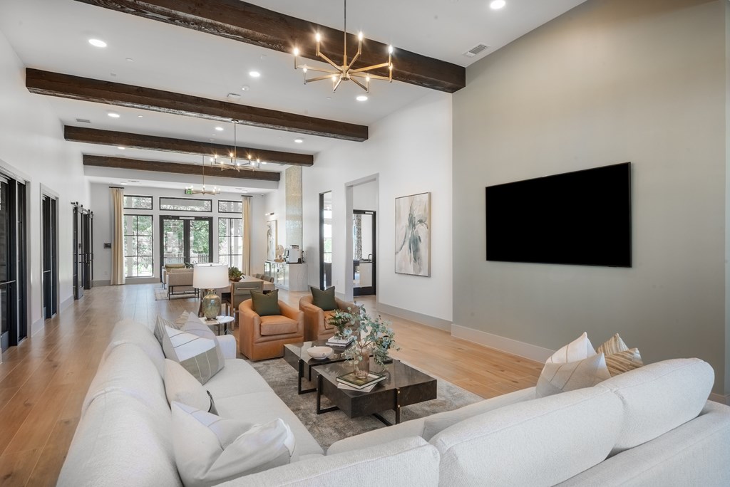A modern living room with a white sofa set and a large TV on the wall.