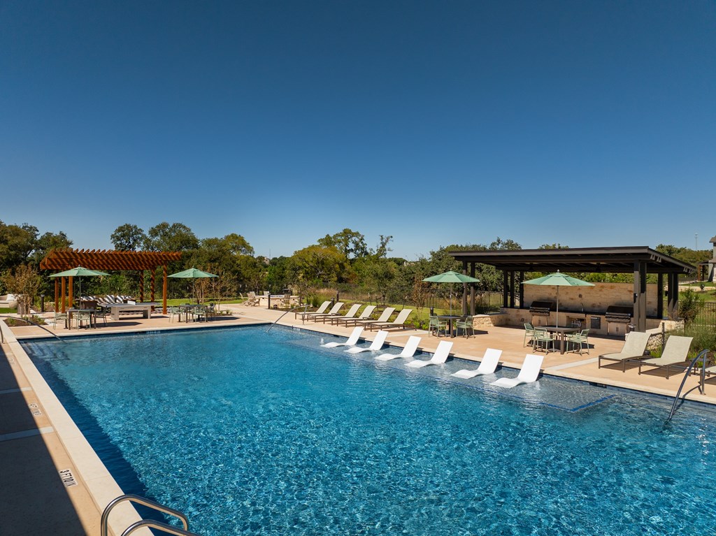 A large swimming pool with lounge chairs and umbrellas.