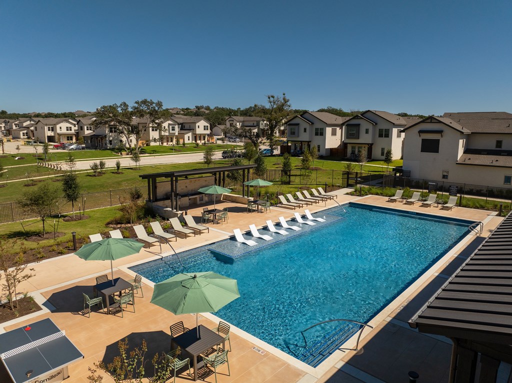A swimming pool surrounded by lounge chairs and umbrellas.