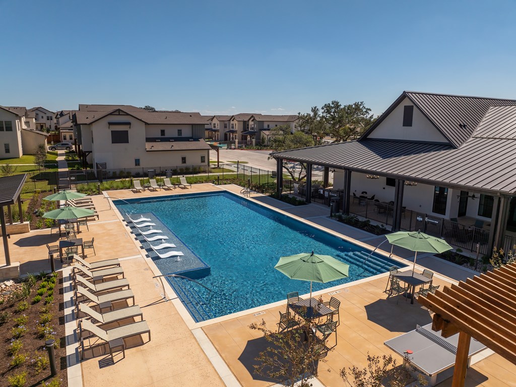 A large swimming pool surrounded by lounge chairs and umbrellas.