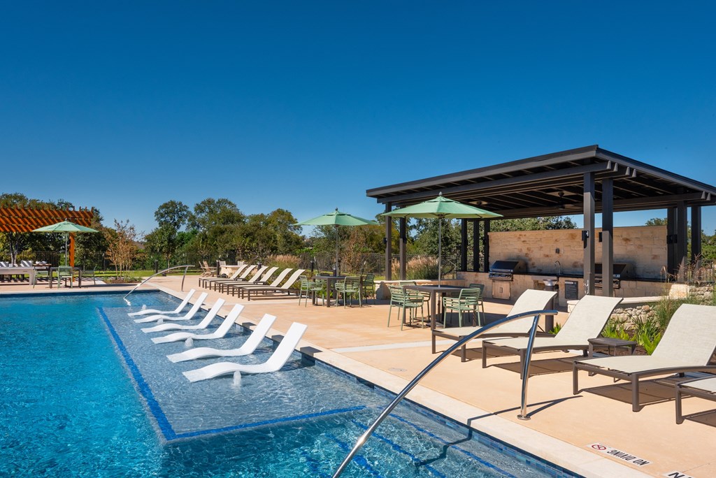 A pool with chairs and a pavilion.
