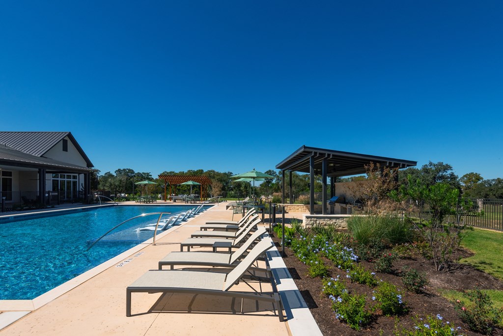 A pool with sun loungers and a building in the background.