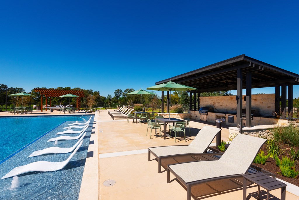 A pool with sun loungers and a pavilion.
