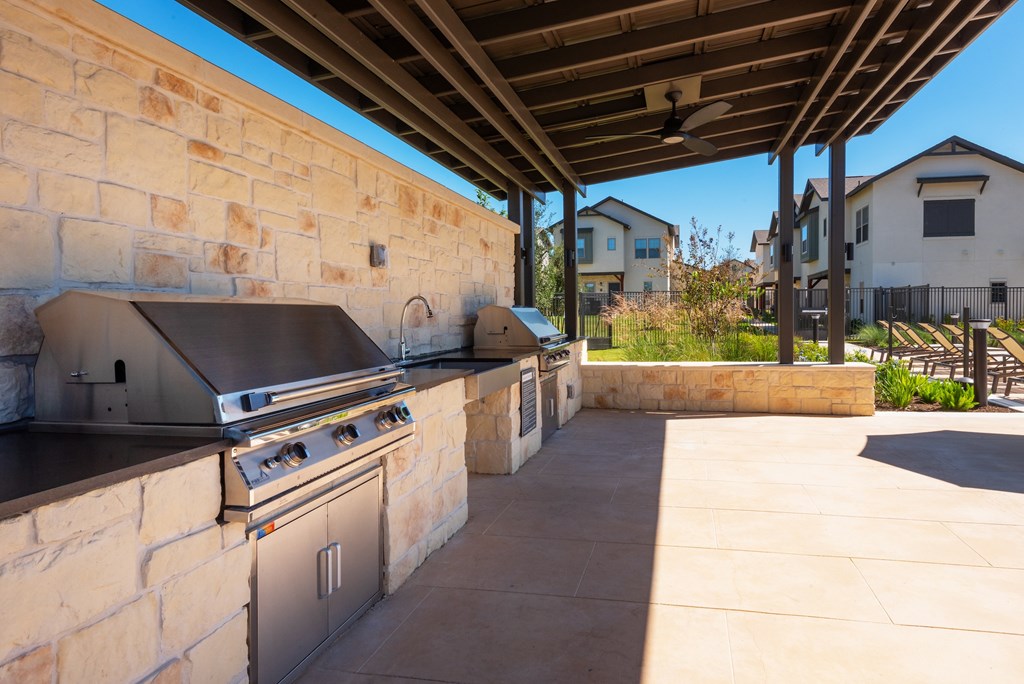 A covered outdoor kitchen area with a grill and sink.