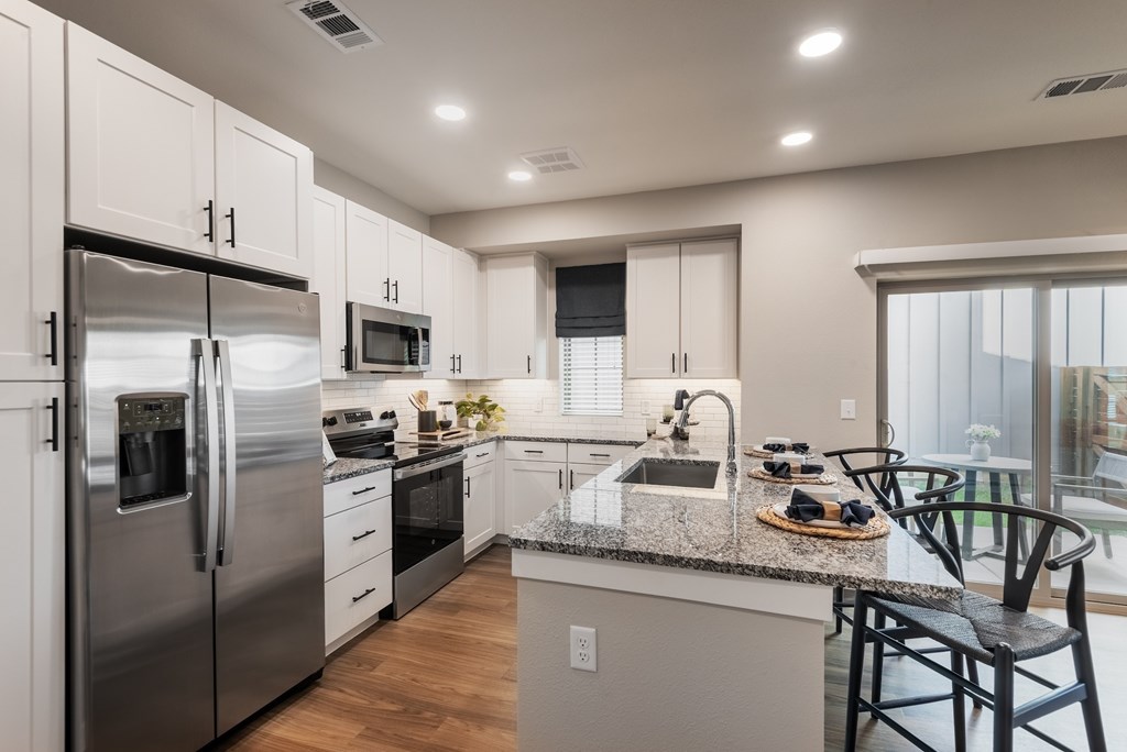 A modern kitchen with stainless steel appliances and a marble countertop.