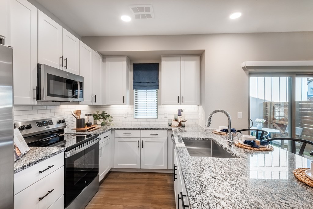 A modern kitchen with granite countertops and stainless steel appliances.