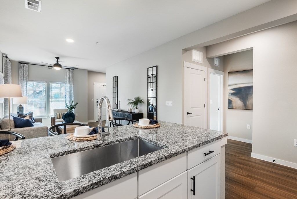 A modern kitchen with a granite countertop and stainless steel sink.