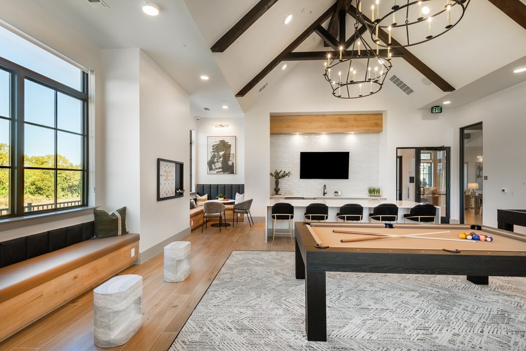 A billiard table is in the middle of a spacious room with a couch and chairs.