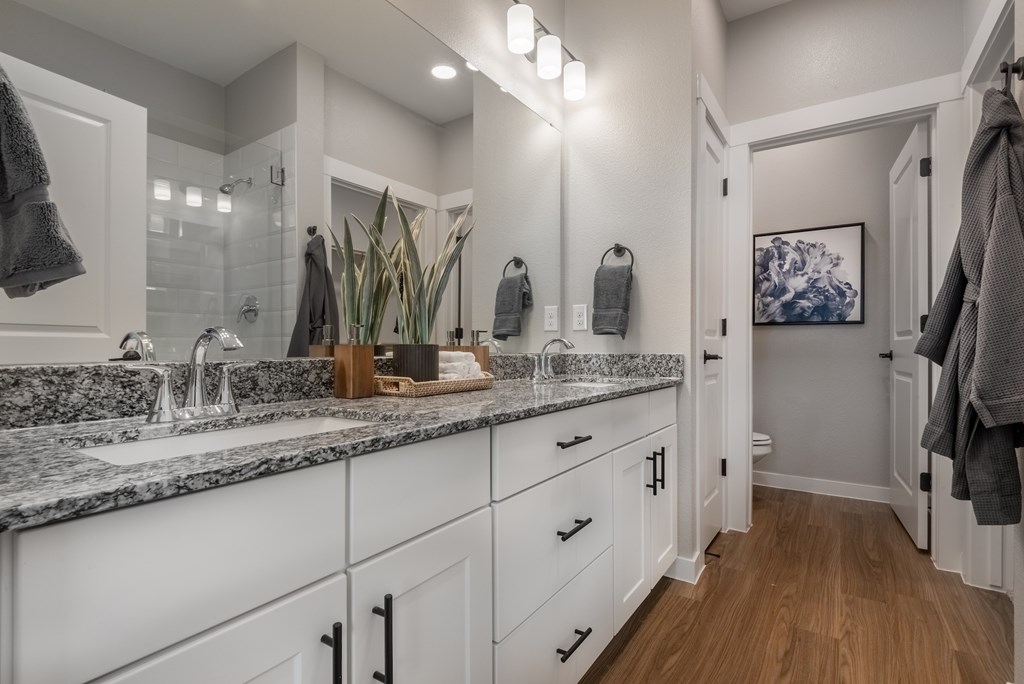 A bathroom with a marble countertop and white cabinets.