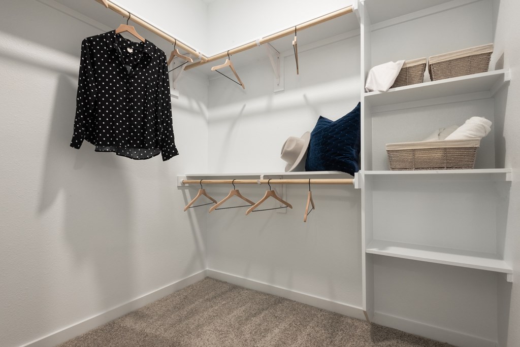 A black shirt with white polka dots is hanging on a white wall.