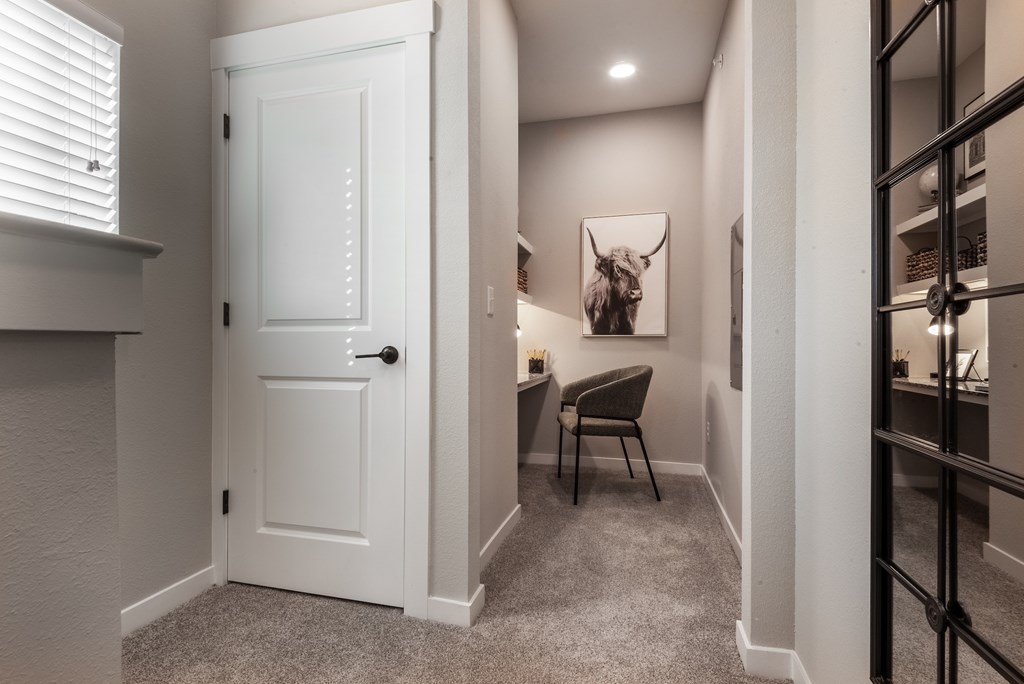 A white door is in a hallway with a chair and a picture on the wall.