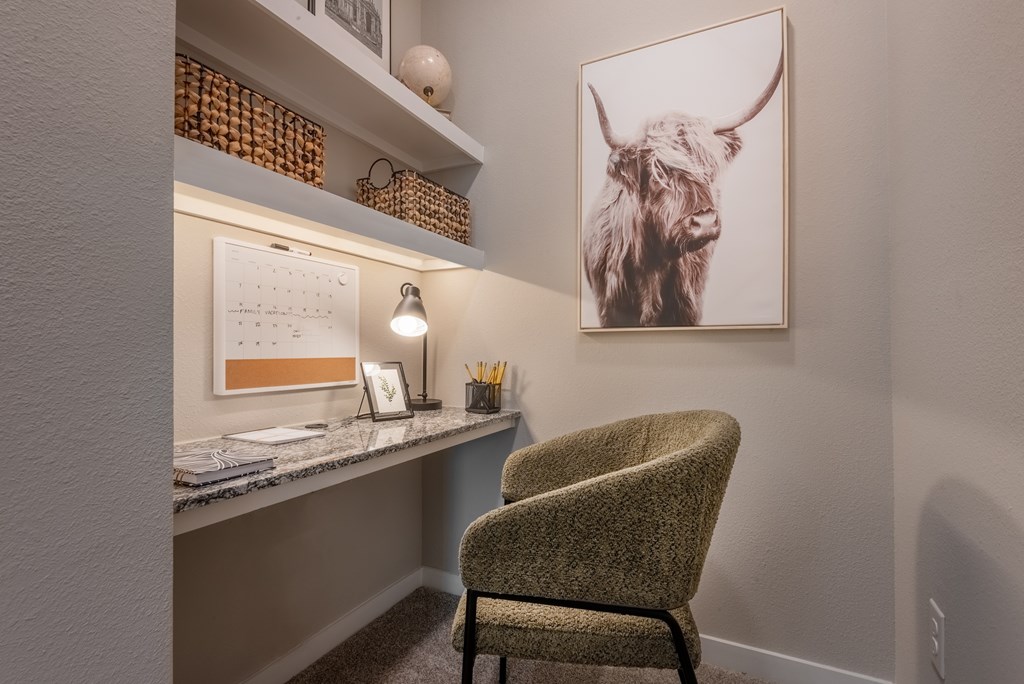 A chair sits in front of a desk with a calendar and a picture of a yak on the wall.
