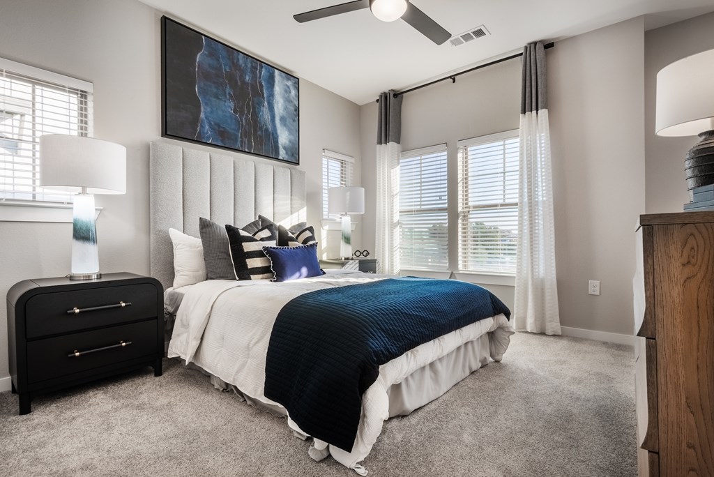 A bedroom with a large bed, a dresser, and a ceiling fan.