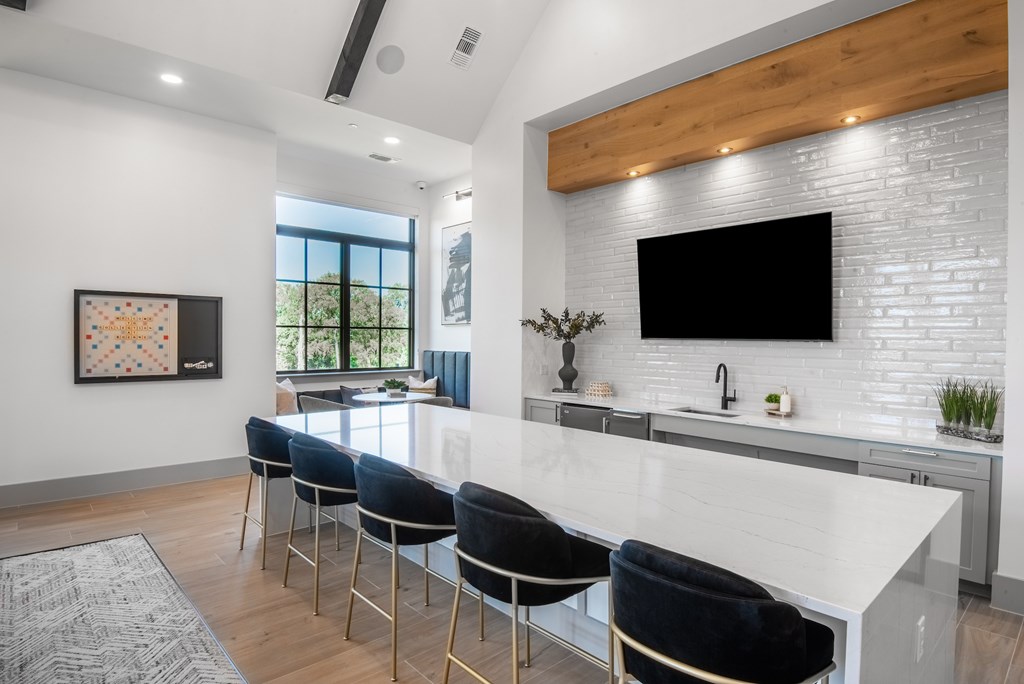 A modern kitchen with a white countertop and black bar stools.