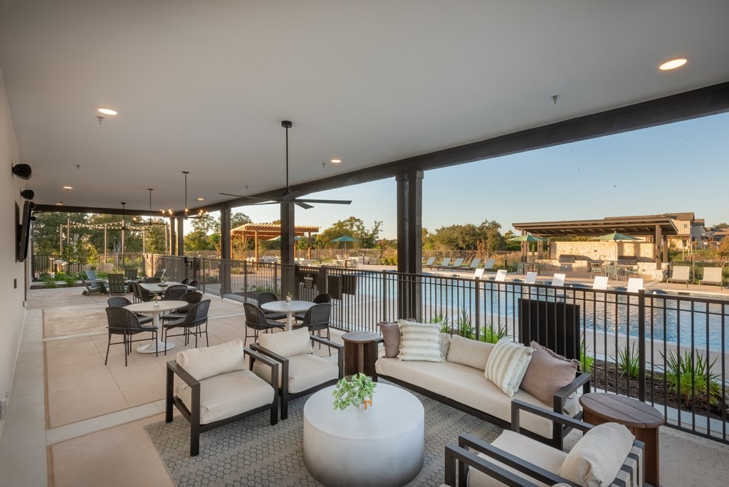 A patio with a table and chairs overlooking a pool.