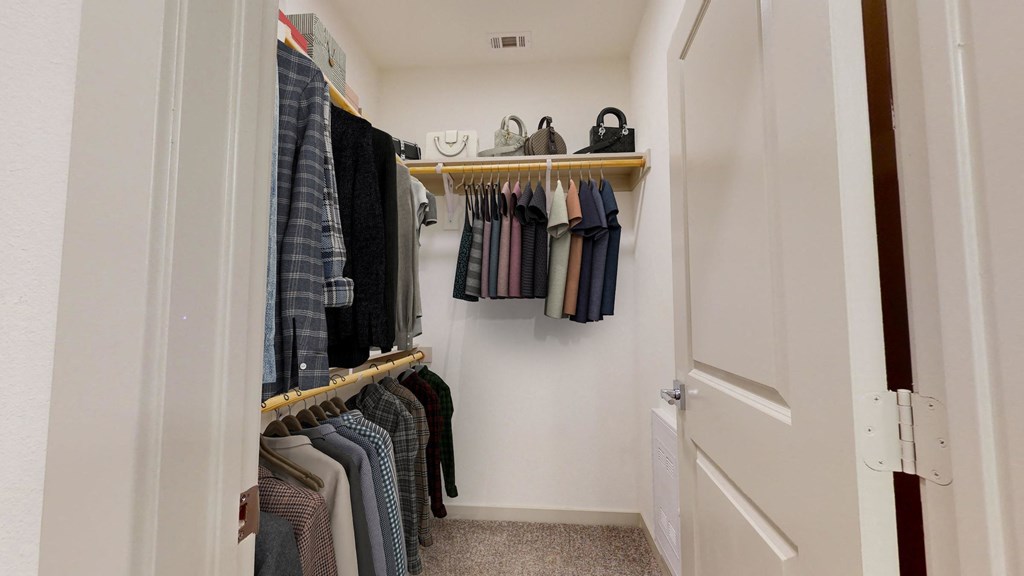 a walk in closet with clothes hanging on a rack and a door