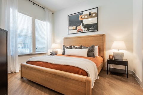 A bedroom with a large bed and a painting above it.