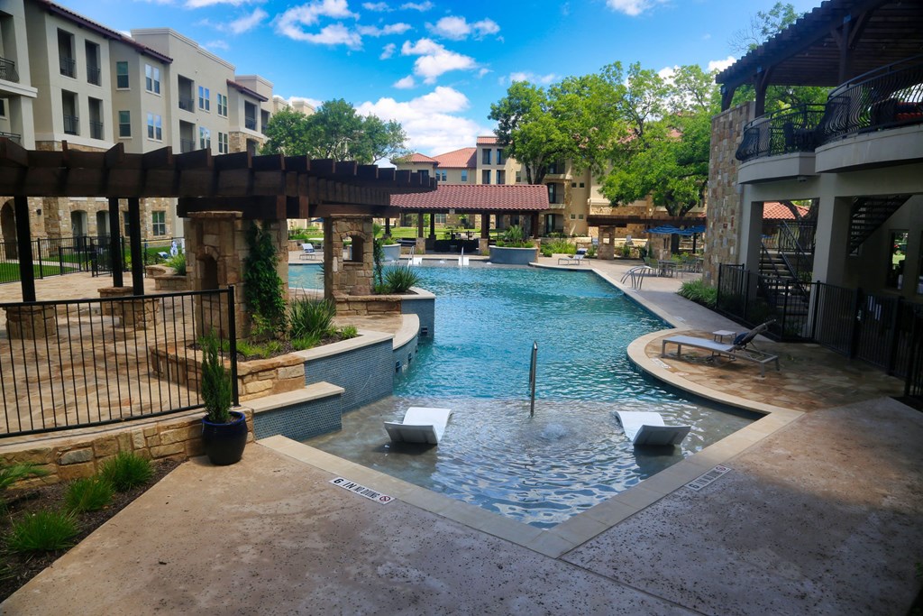 a resort style pool with a spa and lounge chairs