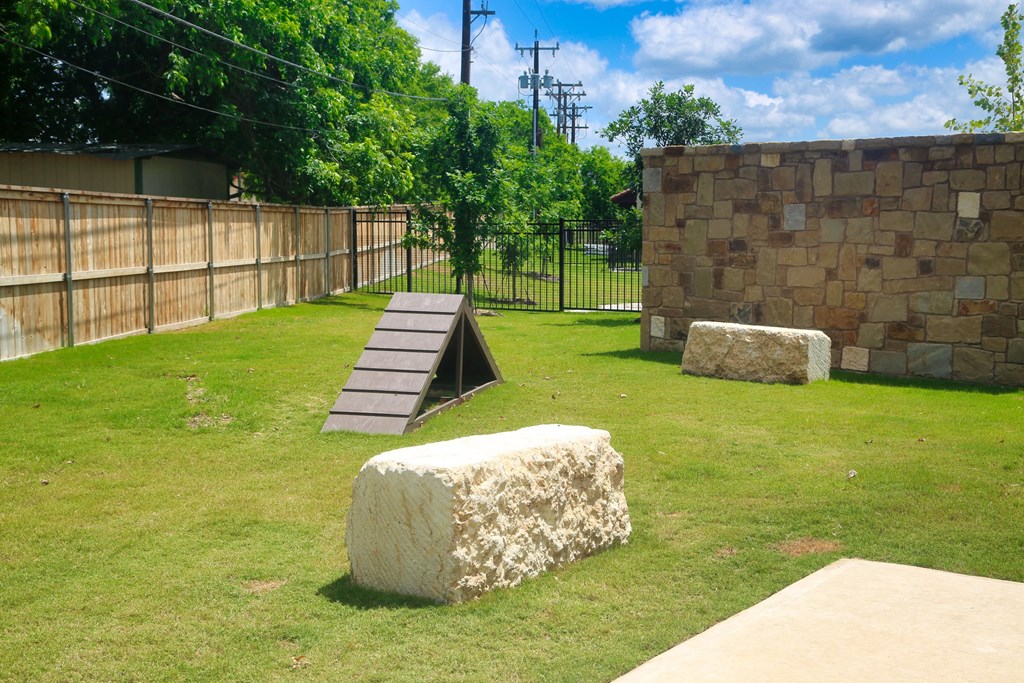 a ramp in a grassy area with a stone wall and trees in the background