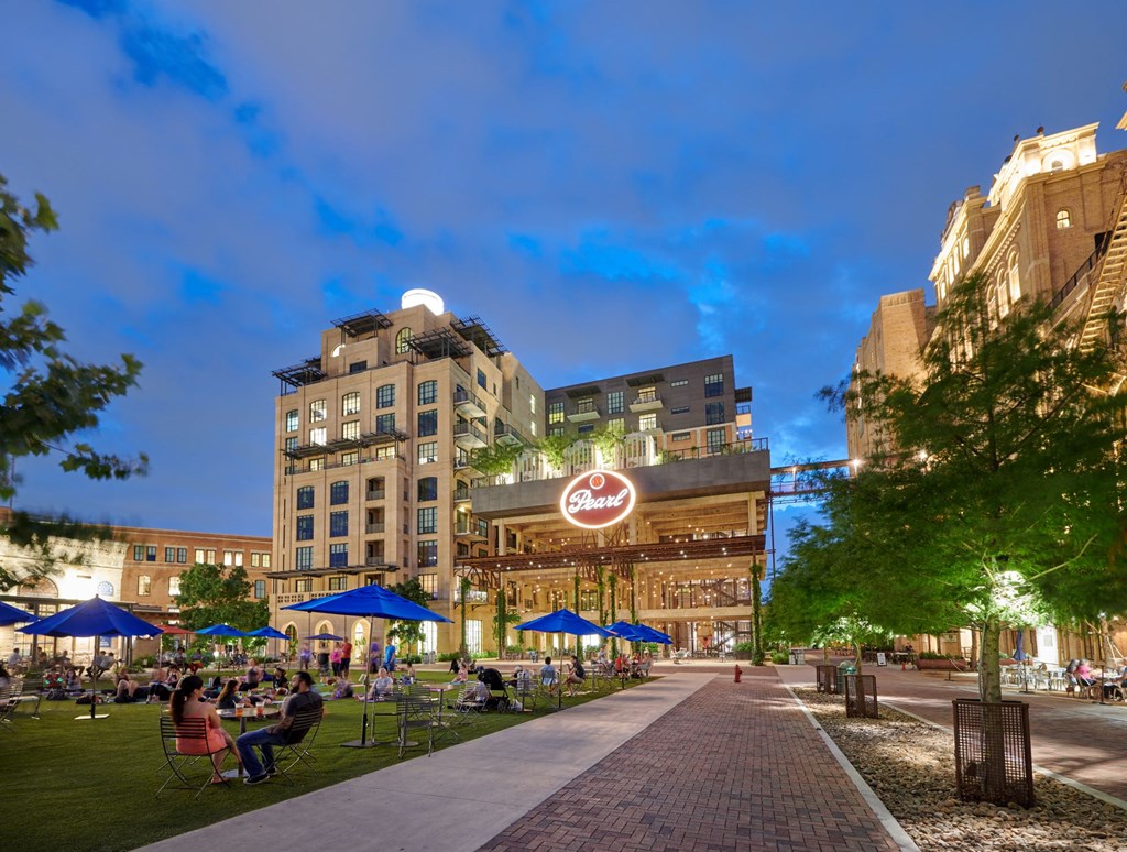 an evening view of a city street with people eating and drinking outside of a building