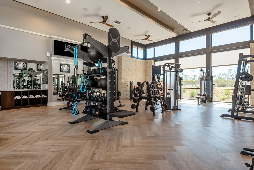 a workout room with weights and other exercise equipment and large windows