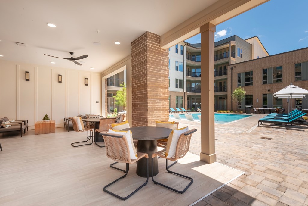 A patio with a table and chairs is covered by a roof.