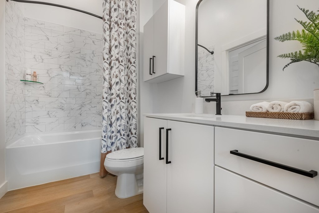 A white bathroom with a marble wallpaper and a white bathtub.