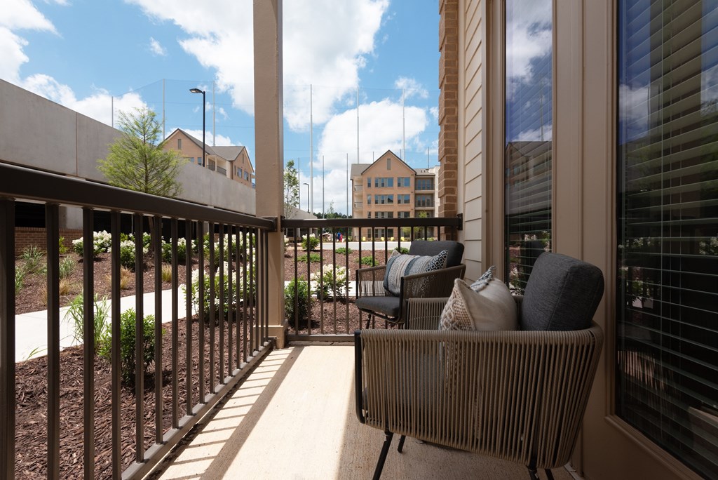 A balcony with a chair and a table with a cushion on it.
