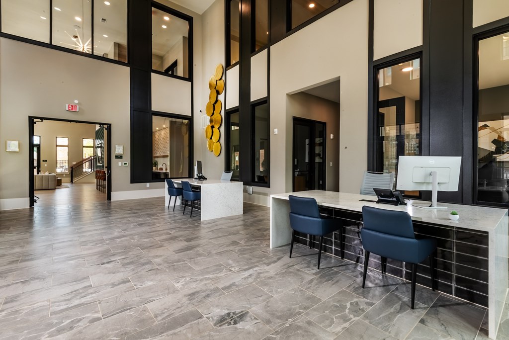 A reception area with a white counter and blue chairs.