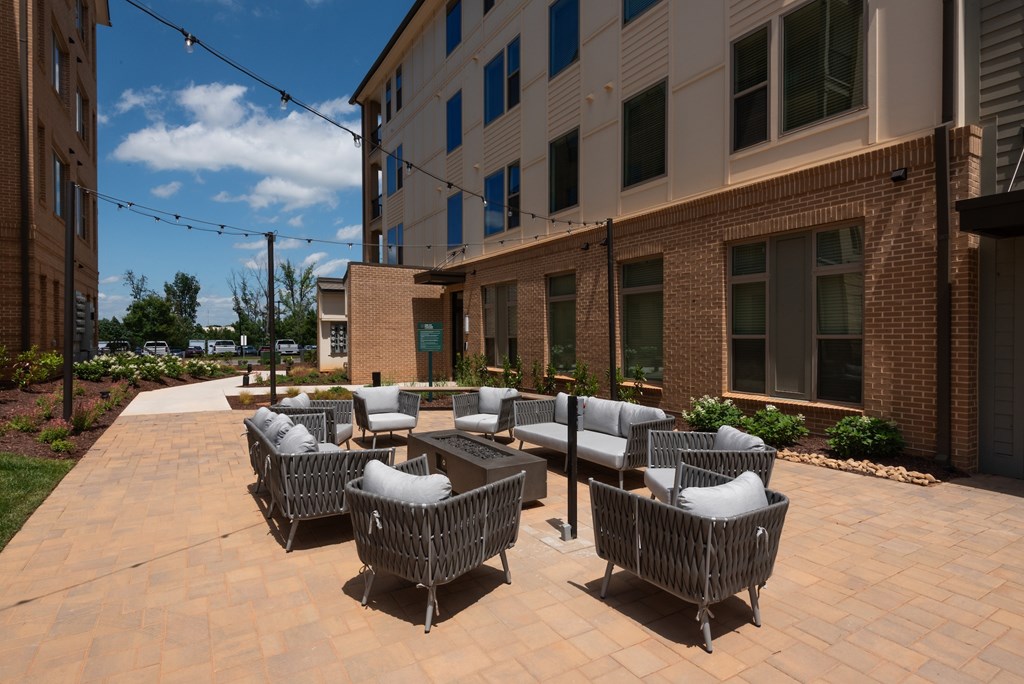 A patio with chairs and tables is surrounded by buildings.