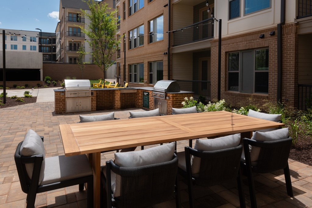 A wooden table surrounded by chairs in a courtyard.