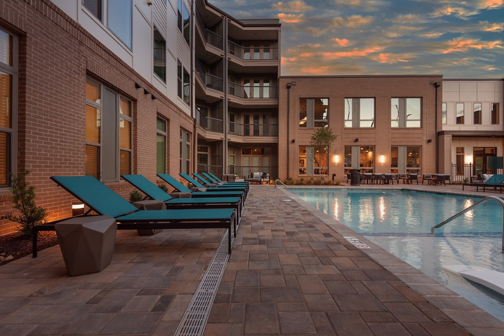 A pool area with lounge chairs and a building in the background.