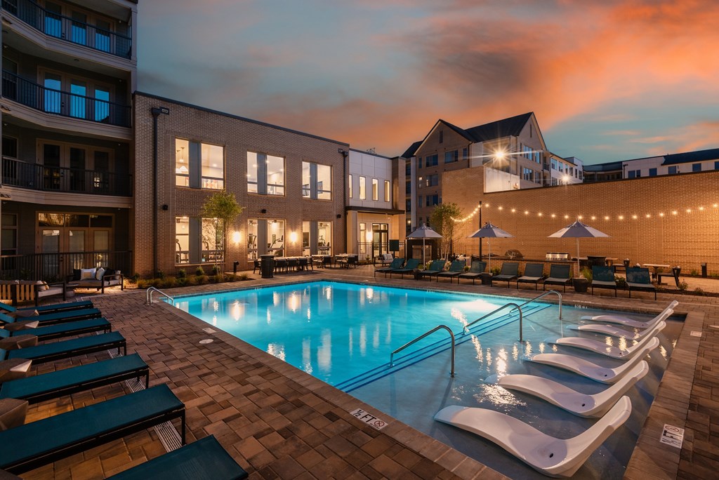 A swimming pool surrounded by lounge chairs and umbrellas.