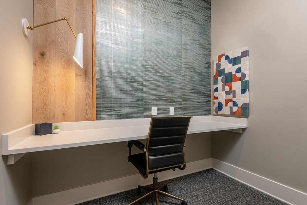 A room with a desk, chair, and a painting on the wall.