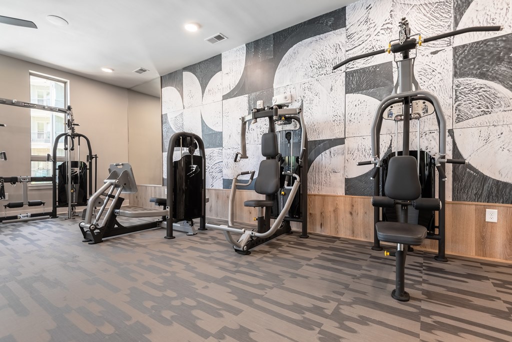 A gym with a variety of equipment including treadmills, stationary bikes, and weight machines.