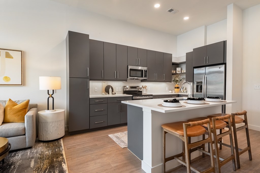 A modern kitchen with a large island and wooden chairs.