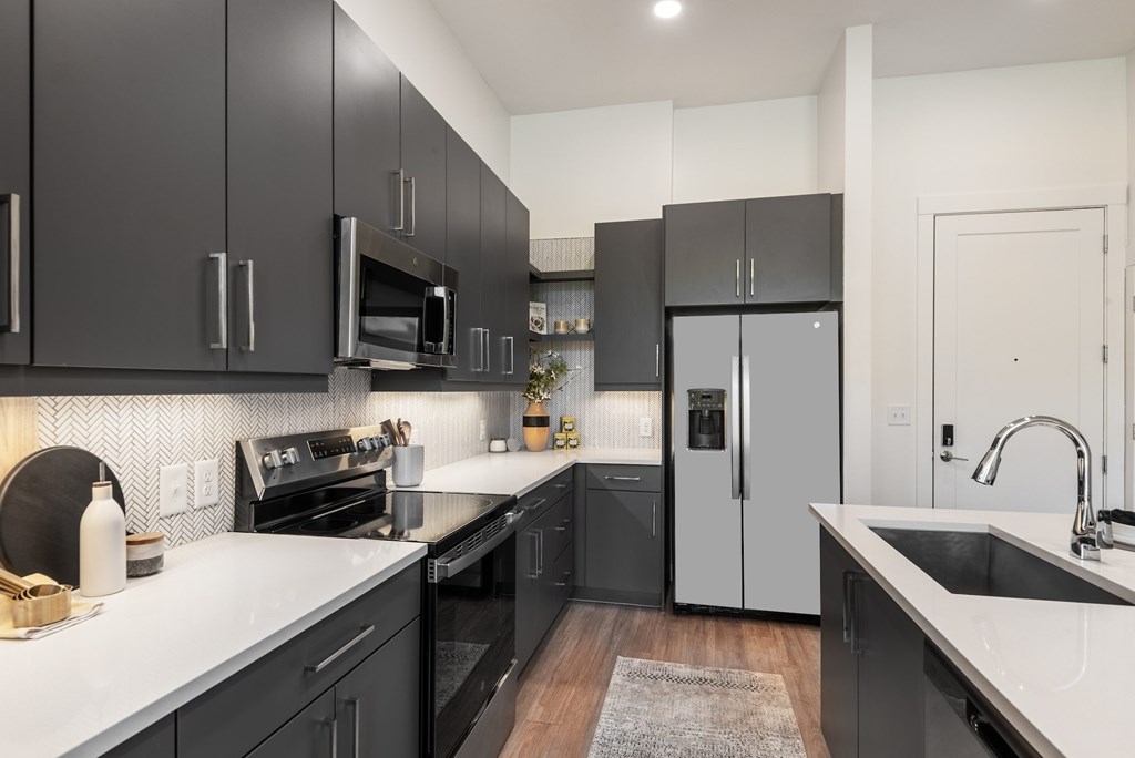 A modern kitchen with black cabinets and stainless steel appliances.