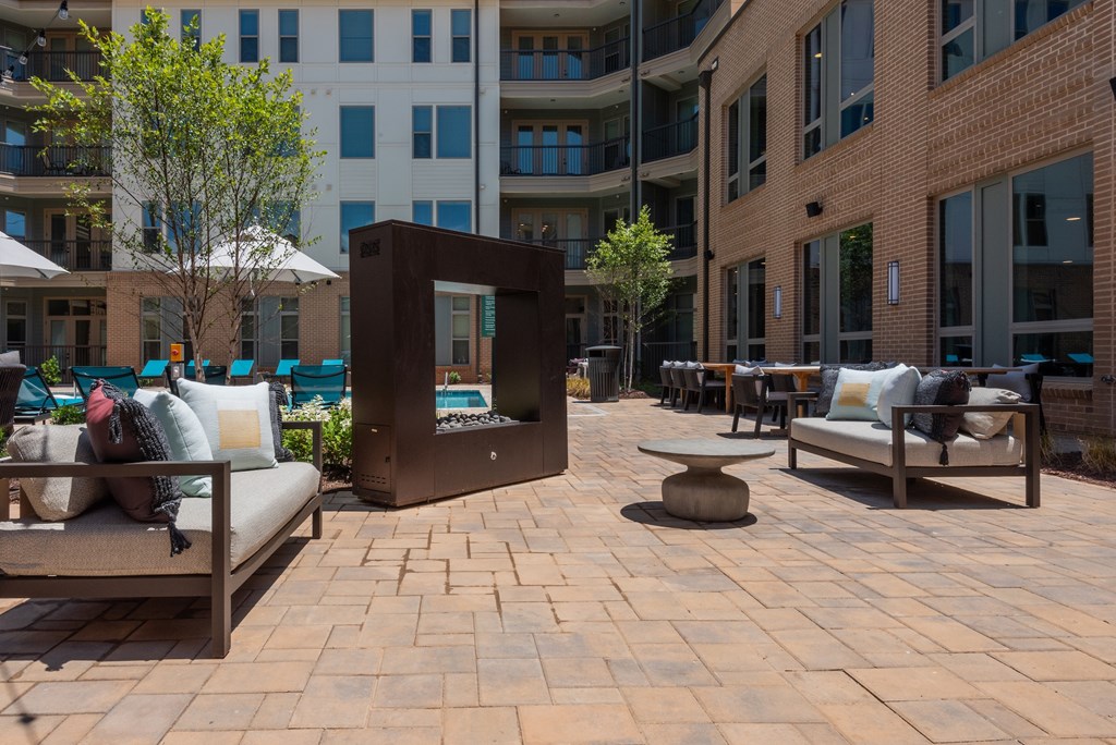 A patio with a couch, chairs, and a table with a fire pit in the middle.
