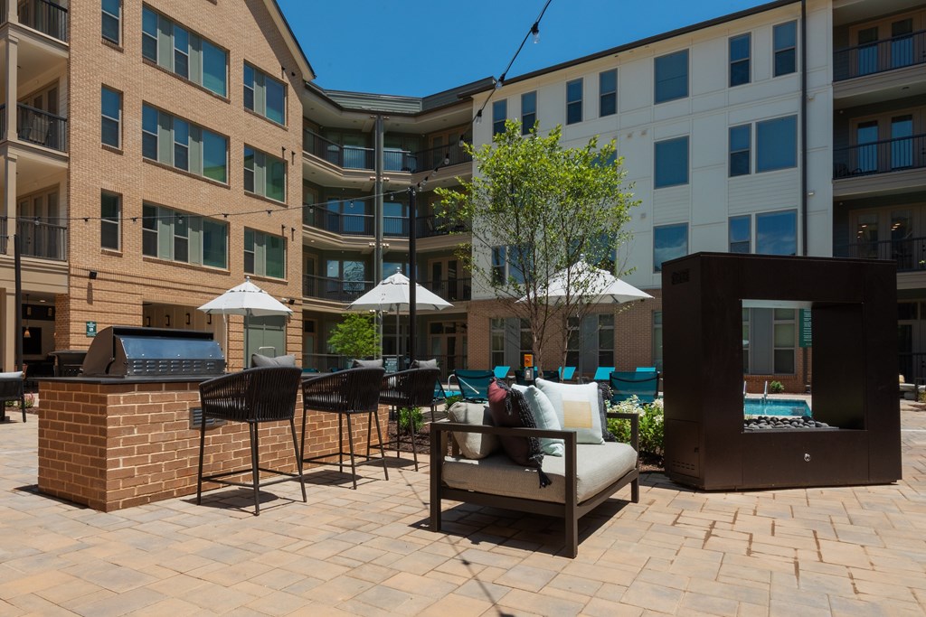A patio area with a brick fireplace, chairs, and umbrellas.