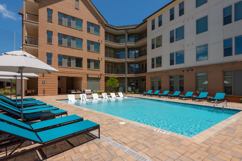 A pool surrounded by blue lounge chairs and umbrellas.